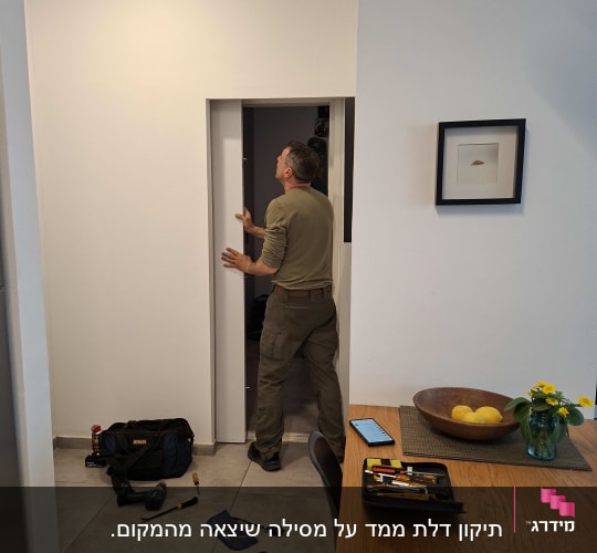 אדם עובד על דלת עם כלים על הרצפה